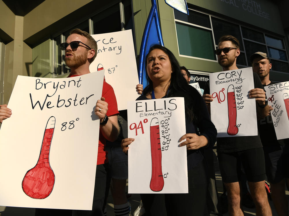Protesters hold up signs outside of the Denver Public Schools administration building to demand equity for students attending classes in excessively hot classrooms.
