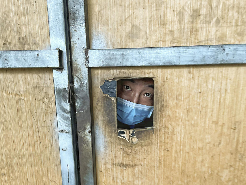 A resident looks through a hole from inside a locked-down area in Beijing on June 30, 2022. China implemented a 