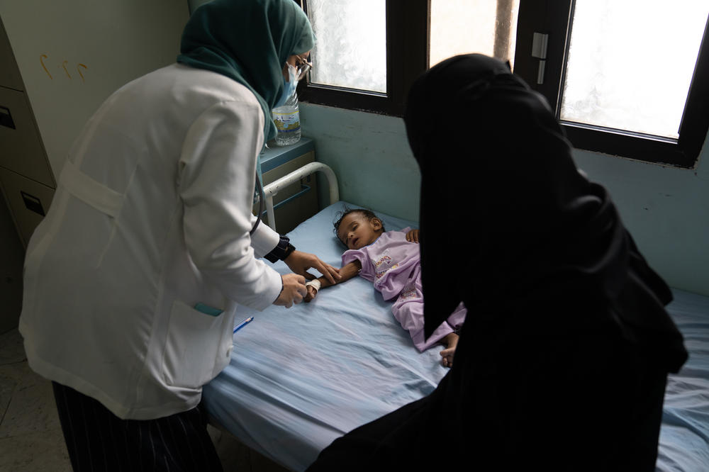 A nutritionist (left) checks a 9-month-old girl who is suffering from dehydration at Al-Thawra hospital in Taiz, Yemen. The girl's condition has improved since she arrived at the clinic.