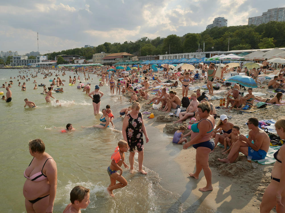 People swim and sunbathe on a reopened beach at the Black Sea on Aug. 22 in Odesa. When missiles and drone attacks first hit the city — and Russian naval vessels started laying explosive sea mines around the port — the beaches were closed. Warning signs urged people to keep their distance.