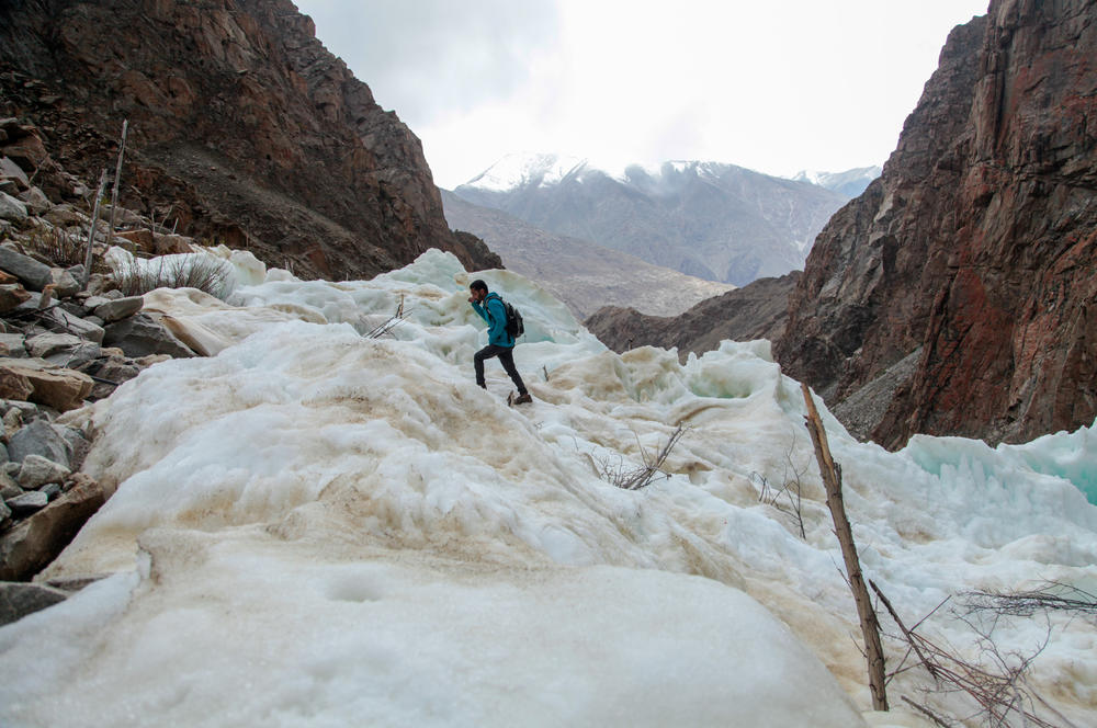 Villager Yasir Parvi, 24, walks on a frozen fountain, or ice stupa, that he helped build over the village of Pari. Pipes that run down from high mountain streams connect to nozzles that spray water into the air, creating a fine mist that freezes in winter, forming a frozen tower that melts in spring, when farmers need water.