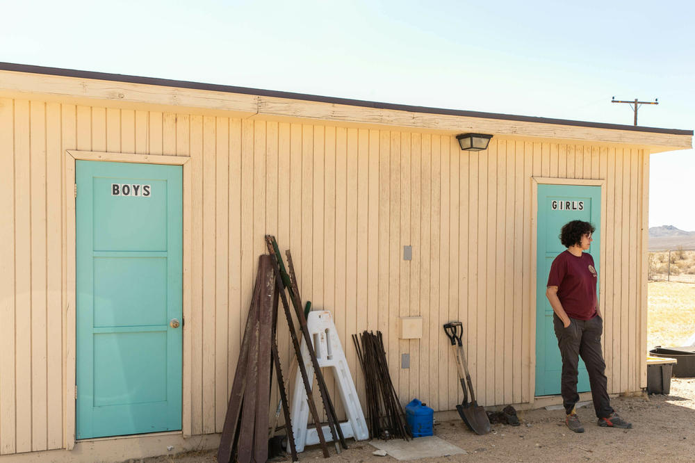 Seed technician Christina Sanchez stands outside the old restroom that's been converted into a seed lab, behind the historic Kelso schoolhouse.