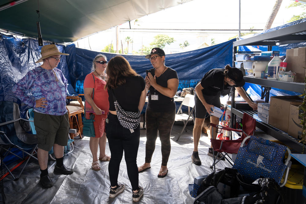 Noelani Ahia (center), an indigenous activist with deep family roots in Lahaina and a co-founder of Maui Medic Healers Hui, talks with volunteers at one of their locations in Lahaina.