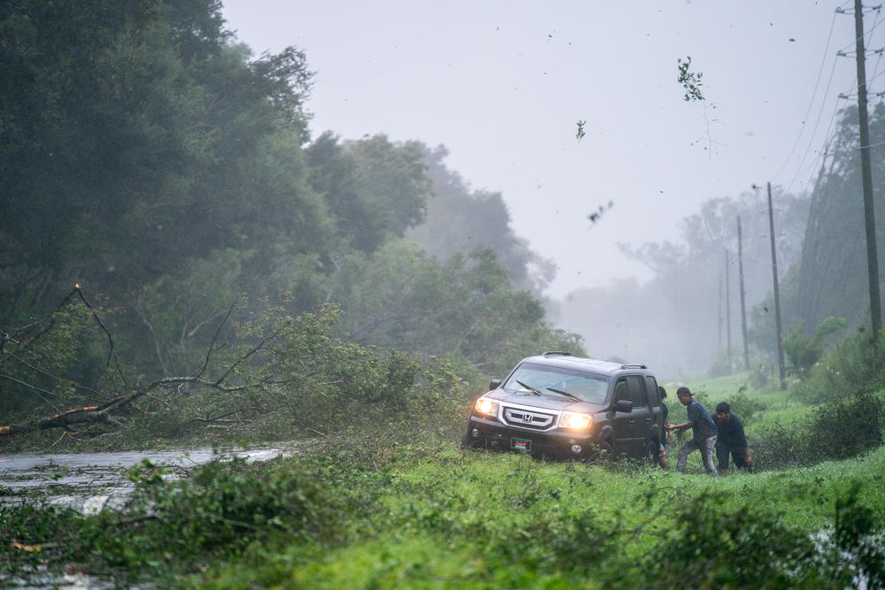 People work to free a vehicle stuck on the shoulder amid storm debris as Hurricane Idalia crosses the state on August 30, 2023 near Mayo, Florida. The storm made landfall at Keaton Beach, Florida as Category 3 hurricane.