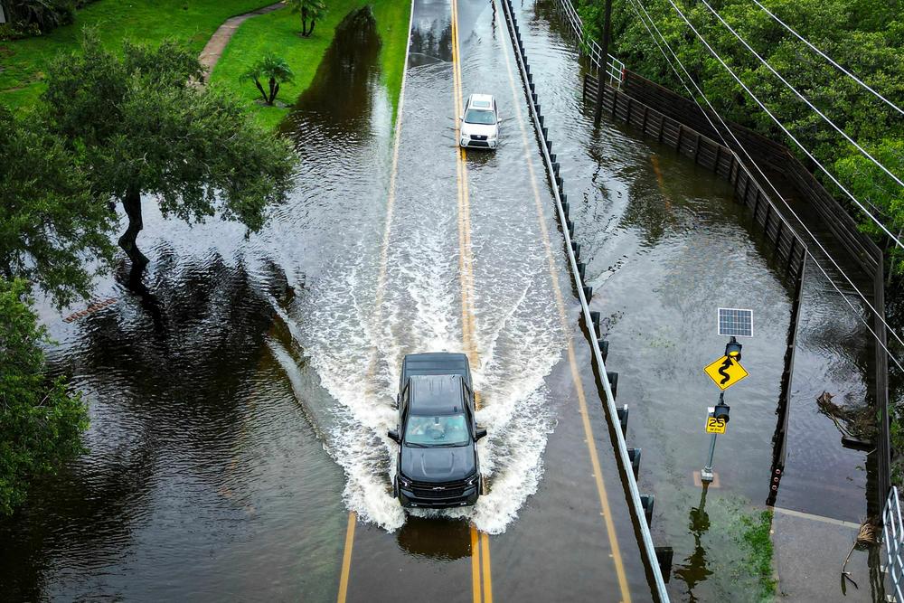 Vehicles attempt to travel on a flooded road in Tampa, Florida, after Hurricane Idalia made landfall.