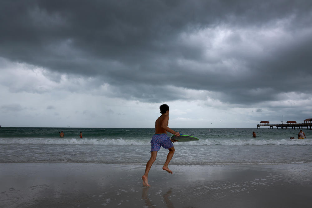 Storm clouds hang over people as they enjoy the beach before the possible arrival of Hurricane Idalia on August 29, 2023 in Clearwater Beach, Florida.