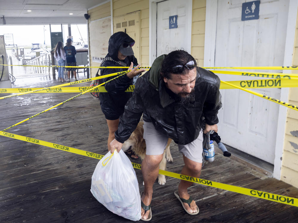 Sailboat owners Shawn Murphy, right, and his wife Sandy Murphy duck under some caution tape as they leave the marina after securing their 48-catamaran at the docks as Hurricane Idalia's bands start to impact the area, Wednesday, Aug. 30, 2023, in Savannah, Ga.