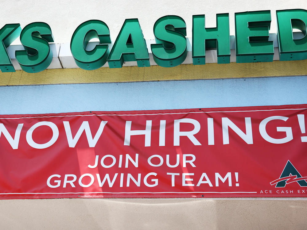 A 'Now Hiring' sign is displayed outside a check cashing shop in Los Angeles on June 2, 2023. Employers added 187,000 jobs in August, while the unemployment rate rose to 3.8%.