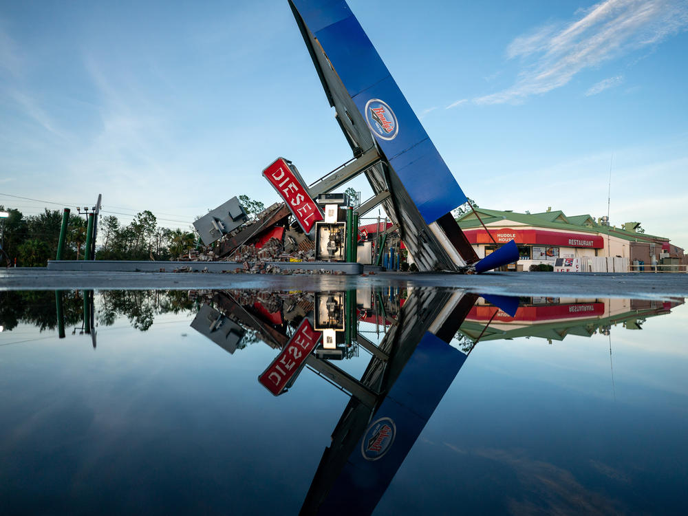 A storm-damaged gas station is reflected in a puddle in Perry, Fla., after Hurricane Idalia crossed the state on Wednesday.