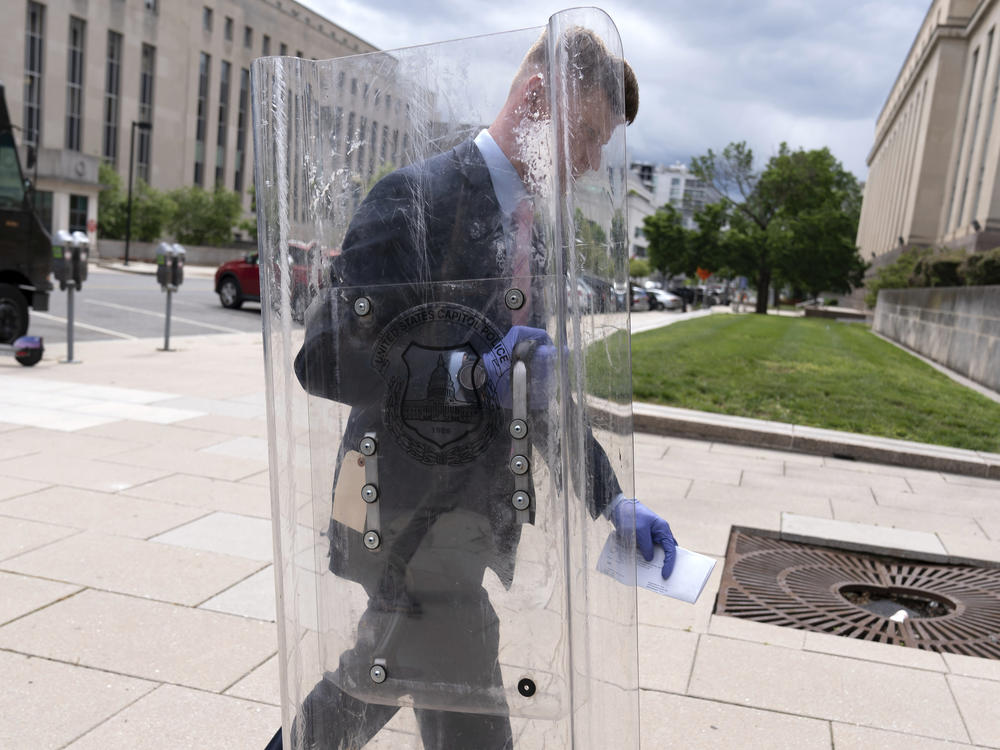 A government official carries a police shield used as evidence against Dominic Pezzola from federal court in Washington, D.C., on May 4, 2023.