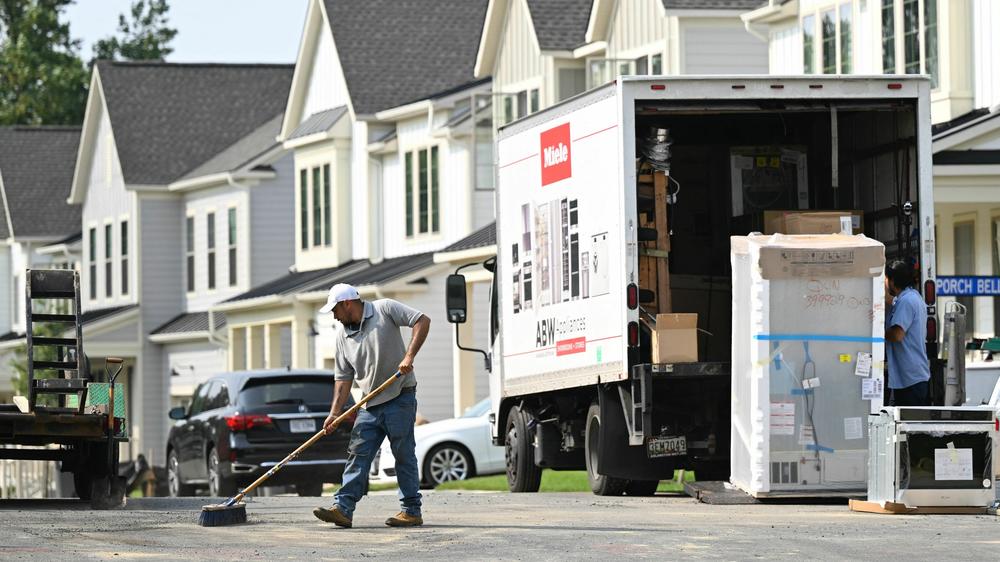 A maintenance worker sweeps the street in front of a row of new homes in Fairfax, Va., on Aug. 22. Sales of new homes are taking off as current homeowners are reluctant to sell their houses, because they would face a higher mortgage for their next one.
