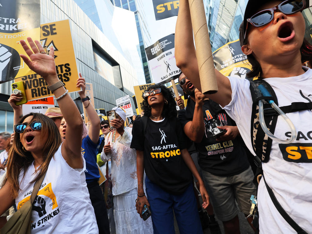 People hold signs as members of SAG-AFTRA and Writers Guild of America East walk a picket line outside of the HBO/Amazon offices during the National Union Solidarity Day in New York City on Aug. 22, 2023. Labor unions have notched some big victories this year but organized labor still faces an uncertain future.