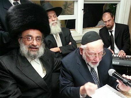 The late Hasidic composer Ben Zion Shenker sings, wearing a yarmulke and holding a mic, at a male-only sing along known as a k<em>umzits </em>that took place in an Orthodox neighborhood in Brooklyn.