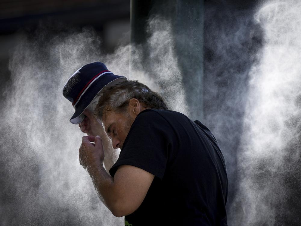 A man cools off at a temporary misting station deployed by the city in the Downtown Eastside due to a heat wave, in Vancouver, British Columbia, Aug. 16, 2023.