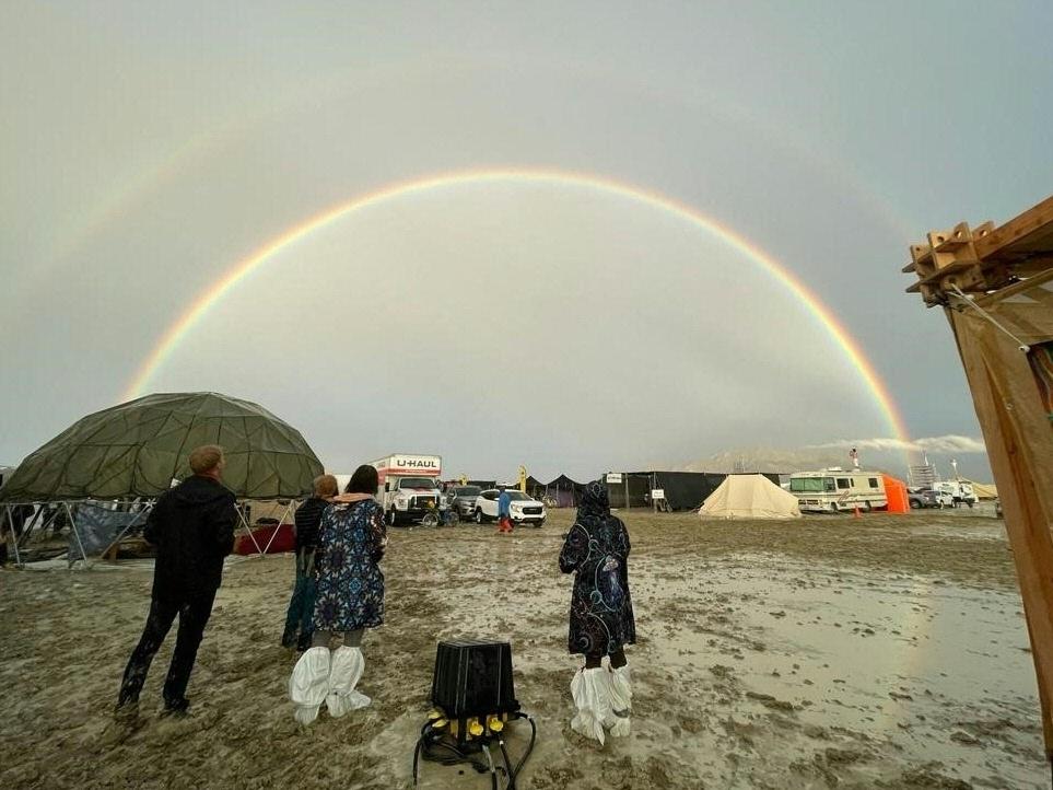 Attendees look at a double rainbow over flooding on a desert plain on Sept. 1, after heavy rains turned the annual Burning Man festival site in Nevada's Black Rock Desert into a mud pit.