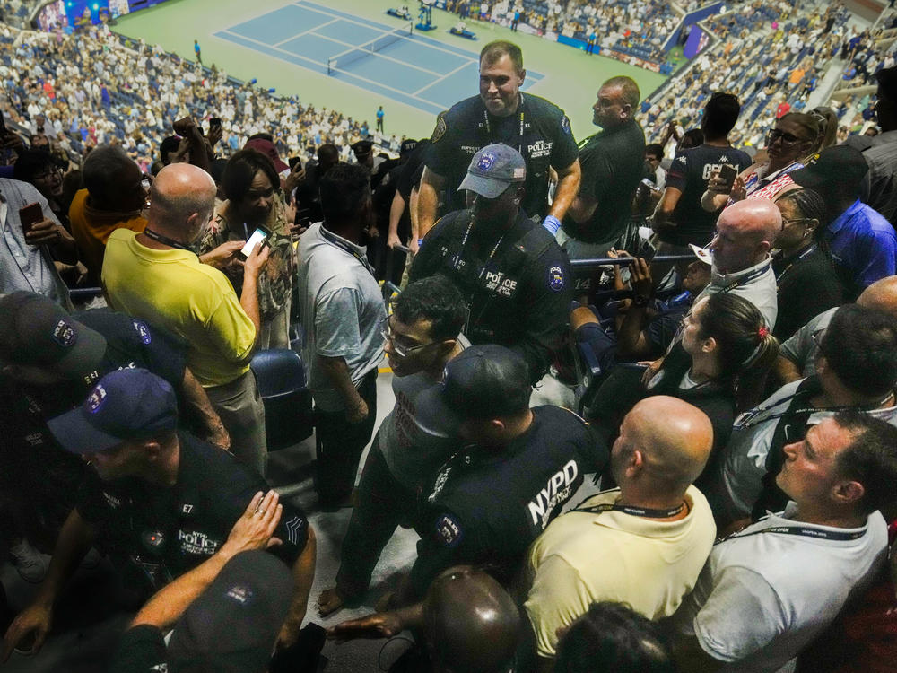 Police officers escort a barefooted protester from the stands during a match between Coco Gauff and Karolina Muchova in the women's singles semifinals of the U.S. Open tennis championships, Thursday, Sept. 7, 2023, in New York.