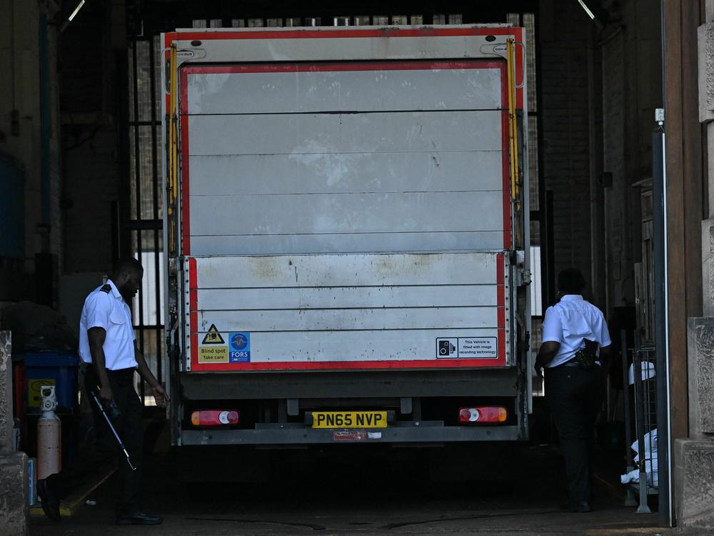 Prison guards walk around the sides of a truck at the gates of Wandsworth Prison in south London on Thursday, a day after terror suspect Daniel Abed Khalife escaped from the prison. British authorities have issued an all-ports alert to track down Khalife, a former soldier awaiting trial on terrorism charges. He escaped from jail by clinging to the bottom of a delivery truck.