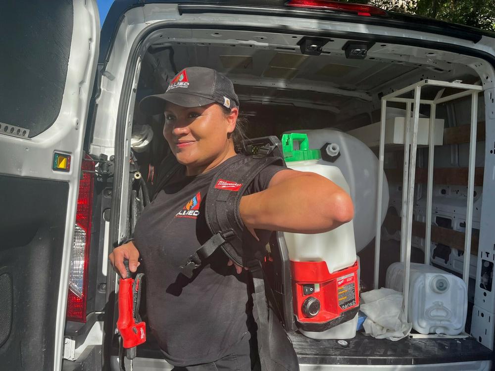 Former firefighter April Schwartz dons a backpack sprayer full of fire retardant to spray the landscaping around a home in Sierra Madre, Calif.