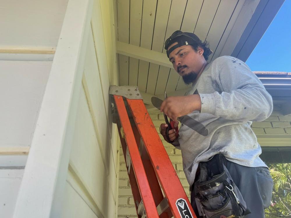Allied Disaster Defense technician Teto Negrete covers air vents with a fine mesh intended to block wind-blown embers from entering the house in the event of a wildfire.