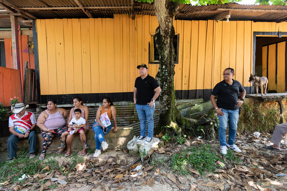 As a bodyguard keeps watch, Molina holds an outdoor meeting to discuss public works projects with neighborhood residents in Cartagena del Chairá.