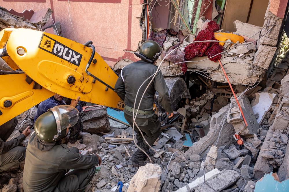 Rescuers use a small excavator to search for survivors under the rubble of a collapsed house in Moulay Brahim, Al Haouz province.