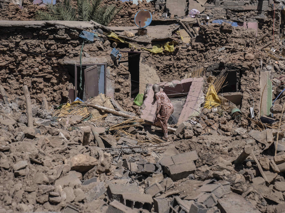 A woman tries to recover some of her possessions from her home which was damaged by an earthquake in the village of Tafeghaghte.
