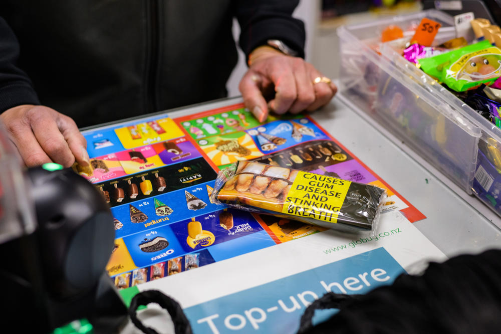 Reetesh Lallu, the third-generation owner of the Hampshire Fruit and Dairy Supply, sells cigarettes to a customer. He estimates that 60-70% of his dairy's revenue comes from cigarettes: 