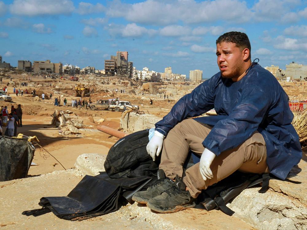 A volunteer takes a break on the rubble of a building in a flash flood-damaged area in Derna on September 14, 2023. The Libyan Red Crescent said Thursday that more than 11,000 were killed in the flood and another 10,000 were still missing.
