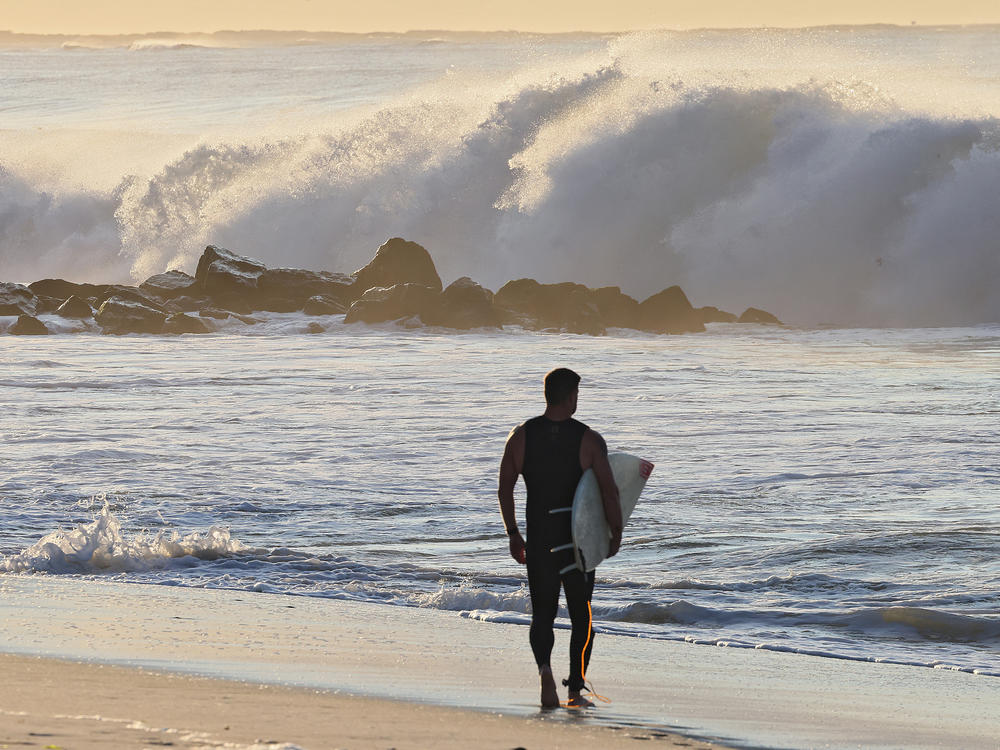A surfer watches higher than normal waves crash ashore in Lido Beach, N.Y. on Thursday, Sept. 14, 2023. Long Island beaches witnessed 8 to 10-foot waves as Hurricane Lee moved toward the New England area.