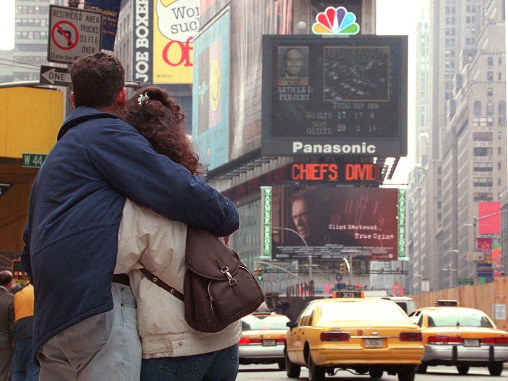 Isabelle and Israel Cerutti of Brazil hug as they watch the NBC jumbotron in Times Square display the 