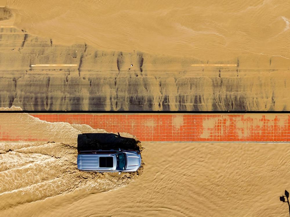 In this aerial picture taken on Aug. 21, a vehicle drives through floodwaters following heavy rains from Tropical Storm Hilary in Thousand Palms, Calif.