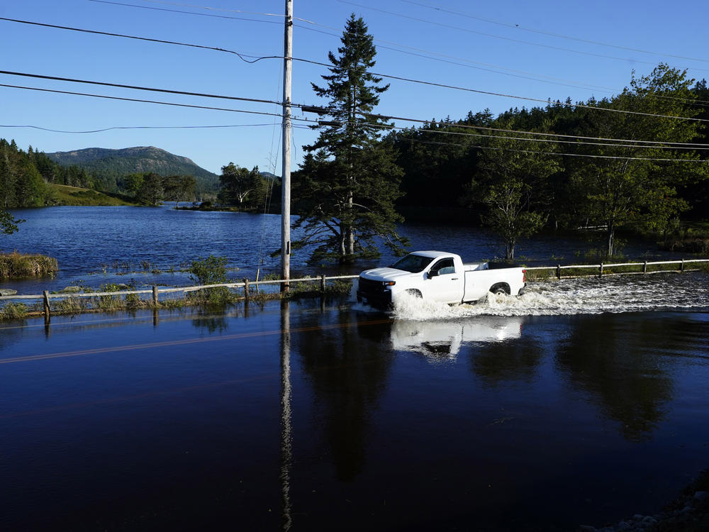 A motorist travels through floodwaters on a road that remains closed a day after Atlantic storm Lee passed through the region, on Sunday, Sept. 17, 2023, near Northeast Harbor, Maine.