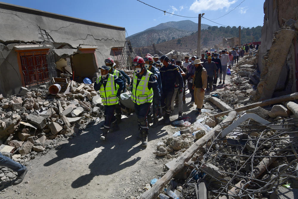 Rescue teams bring the body of an earthquake victim, which they have spent hours freeing from the rubble, off the mountain in Imi N'Tala, Morocco, on Sept. 13.