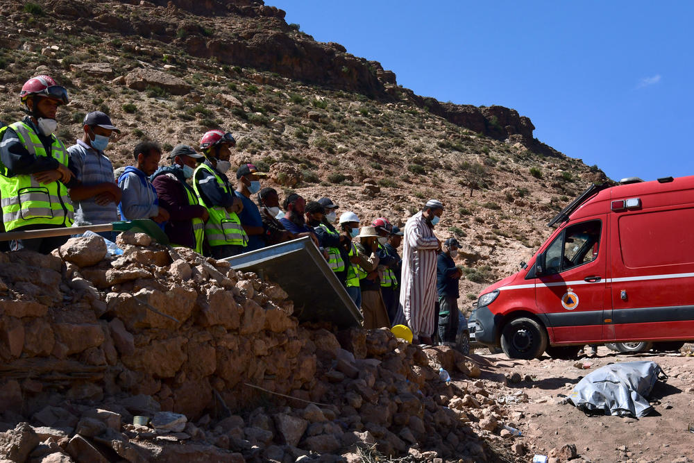 Rescue teams and civil protection members pray as a body is buried in Imi N'Tala, Morocco, on Sept. 13.