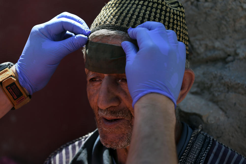 A man injured in Morocco's earthquake gets his head bandaged by a civil protection worker in Imi N'Tala, Morocco, on Sept. 13.