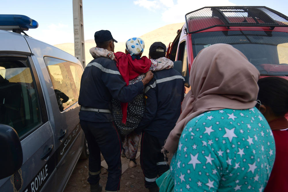 Walking wounded residents wait as rescue teams and civil protection members search the rubble for bodies of victims who perished in Imi N'Tala, Morocco, on Sept. 13.