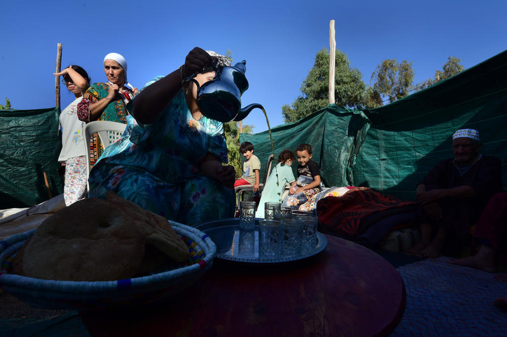 Erbeen's mother pours tea and offers food to family members and guests.