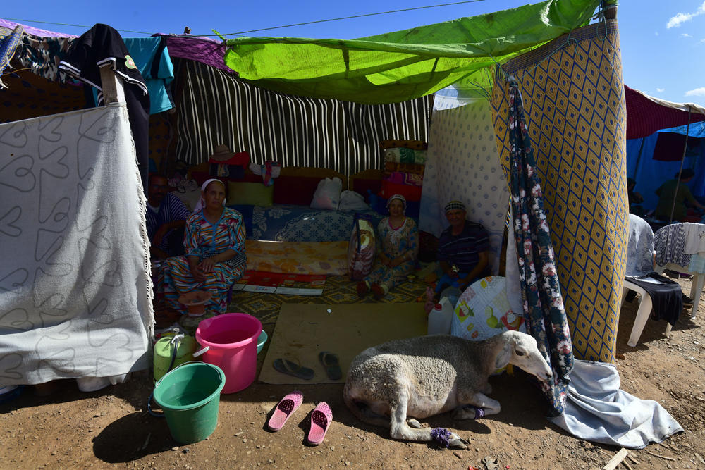 Erbeen's neighbors sit in a tent near their street, which was reduced to rubble, on Sept. 11. Their sheep has a broken leg from the earthquake.