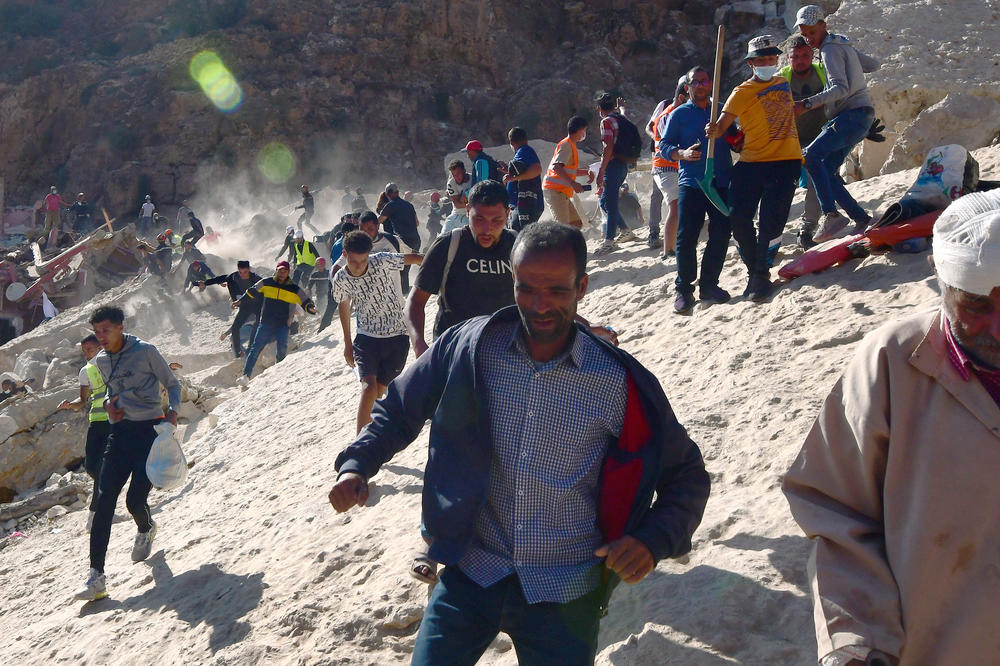 Civil protection and rescue workers who had been digging out a body from the rubble of a devastating earthquake run in panic during an aftershock in Imi N'Tala, Morocco, on Sept. 13. There is danger of more rock falling from the mountain that destroyed the town.
