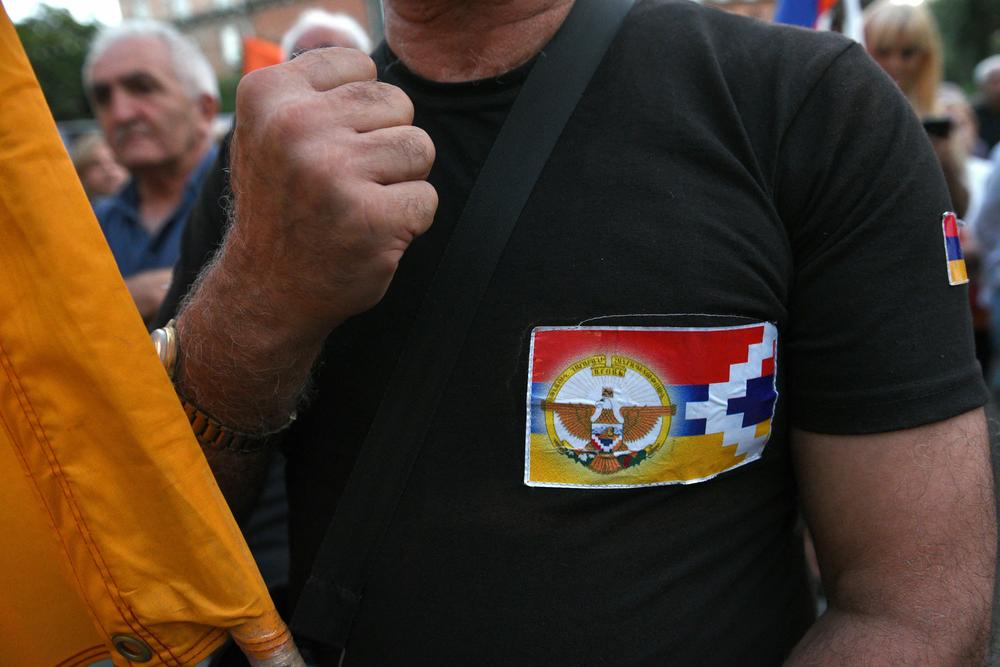 A demonstrator wearing a sticker with the flag of the Nagorno-Karabakh region raises his fist during a rally in central Yerevan, Armenia, Sept. 14.