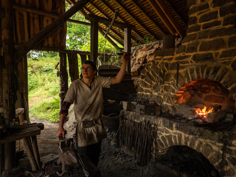 Matisse Lacroix, 20, a blacksmith at Guédelon Castle, works a large bellows to make the fire hot enough to melt iron and make it malleable.