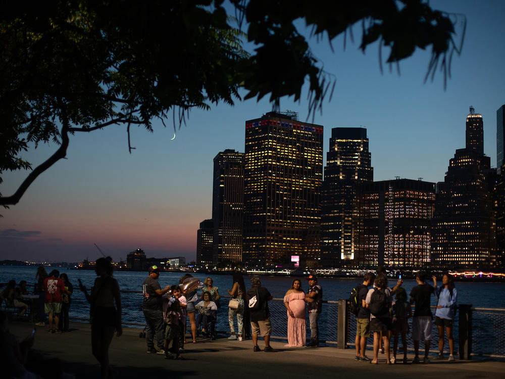 Trees and other plants help keep cities cooler. In New York City, scientists are working to understand how to maximize the benefits of urban green spaces. Here, residents gather in Brooklyn Bridge Park on a hot summer night.