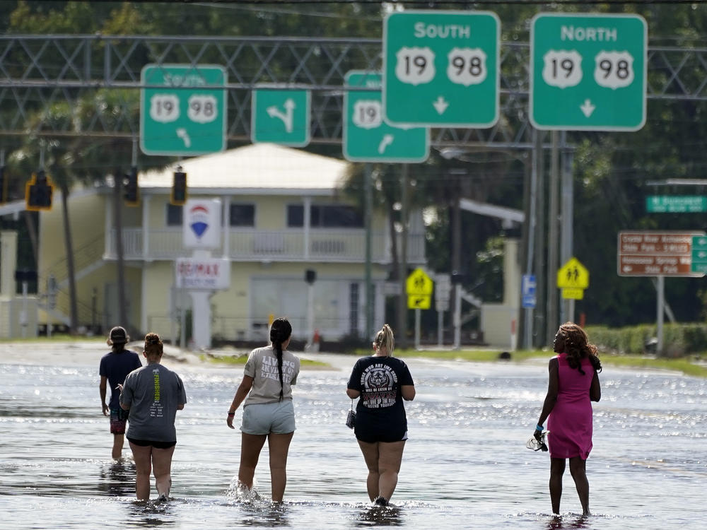 People walk through flood waters last month in Crystal River, Fla. Hurricane Idalia made landfall along the Big Bend region of Florida.