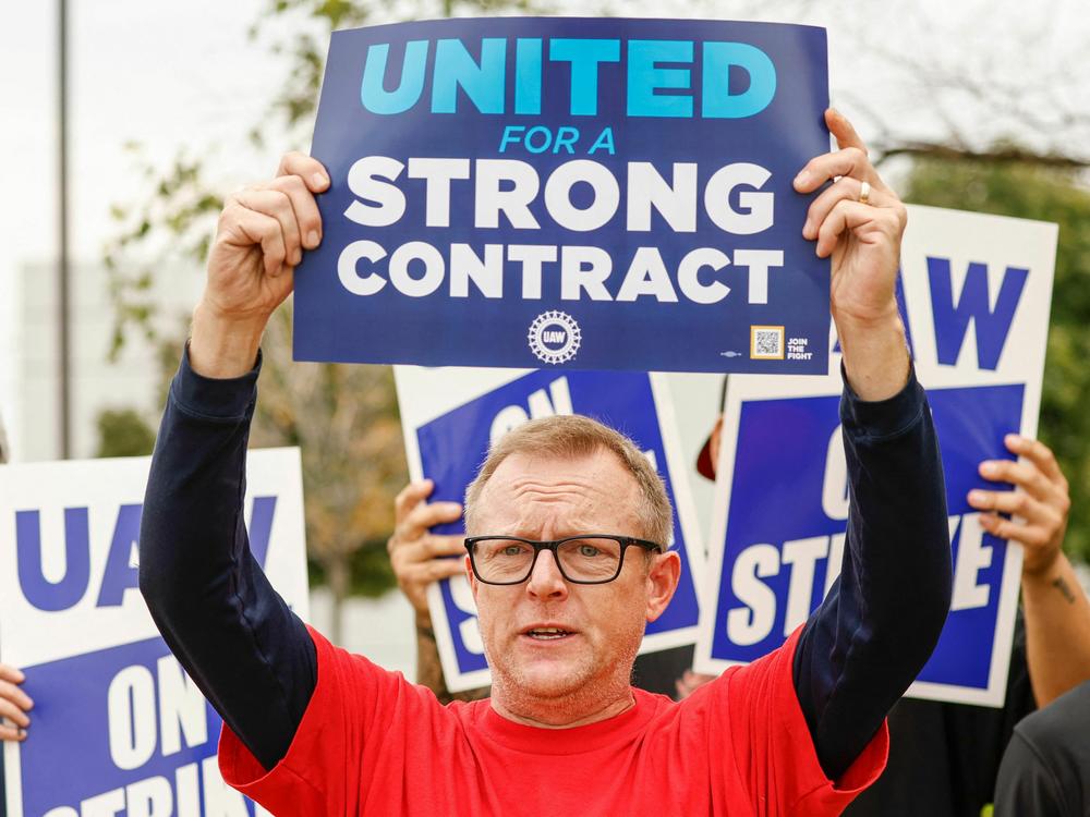 UAW members hold signs outside after walking out from the GM parts distribution center in Bolingbrook, Ill., on Sept. 22, 2023. President Biden said he would join workers on the picket line in Michigan next week.