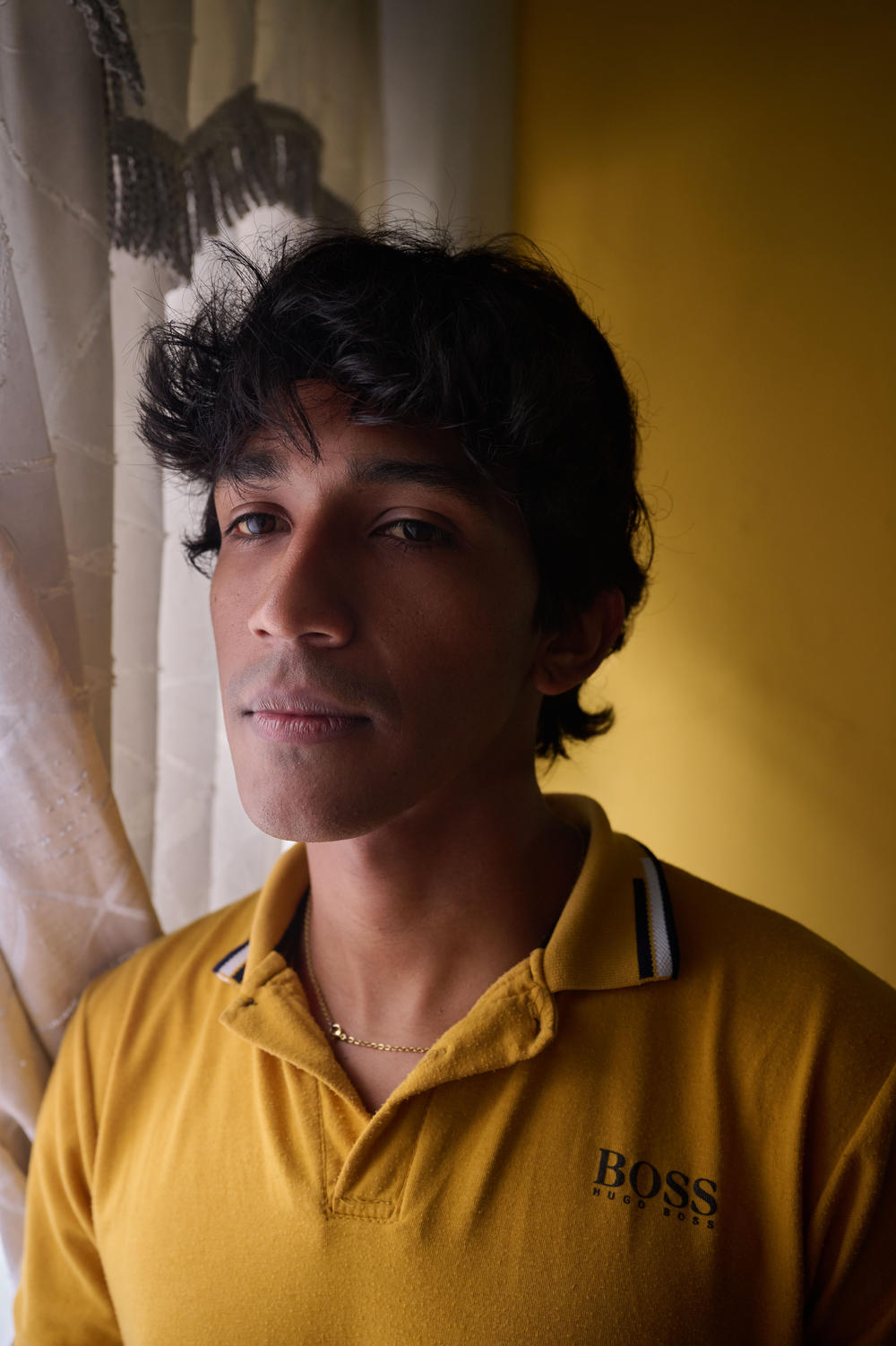 David, 28, poses for a portrait in his room that he rents with his mother. Originally from Aragua, Venezuela, David emigrated to Colombia accompanying his sister-in-law and her children. 