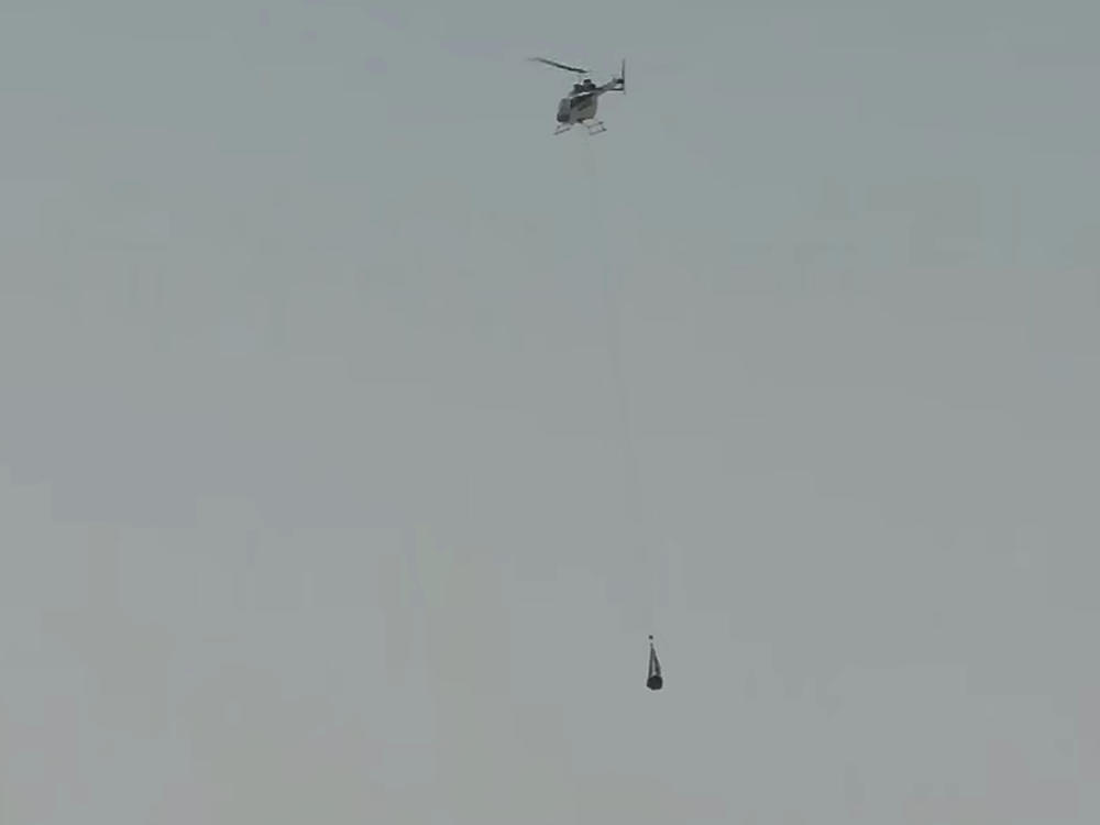 This image taken from video provided by NASA TV shows the capsule released by the Osiris-Rex spacecraft being lifted off by a helicopter after landing to Earth in Utah.