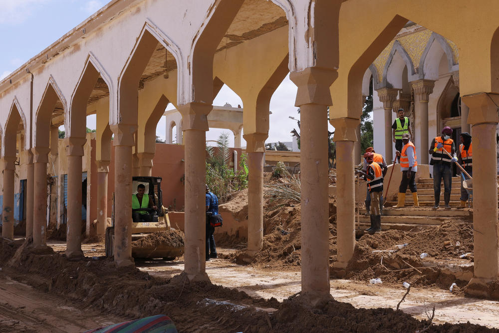 Workers move piles of mud and dirt outside a Derna mosque following fatal floods, Sept. 18.
