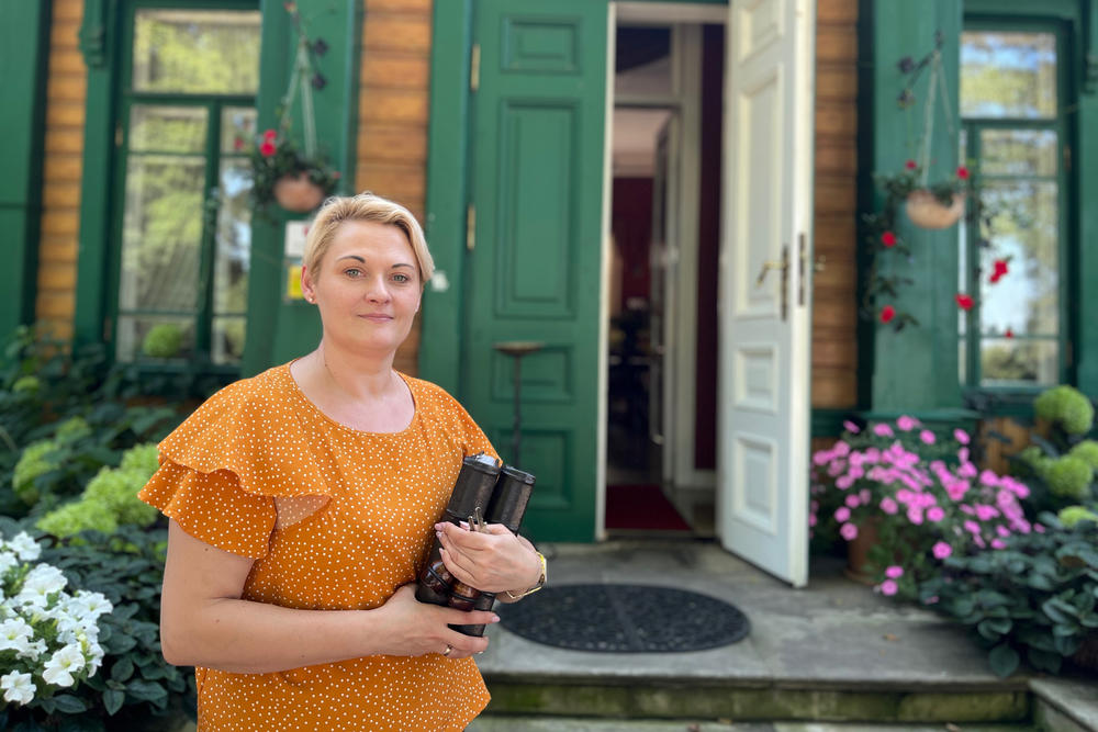 Magdalena Ostrowska stands in front of her restored 19th century hotel and restaurant in Bialowieza, along Poland's border with Belarus. Tensions along this border have meant that Ostrowska's revenue has been cut in half. She says guests cancel their reservations because they are scared of Polish media reports that say Russia's Wagner militia is training just beyond the border in Belarus.