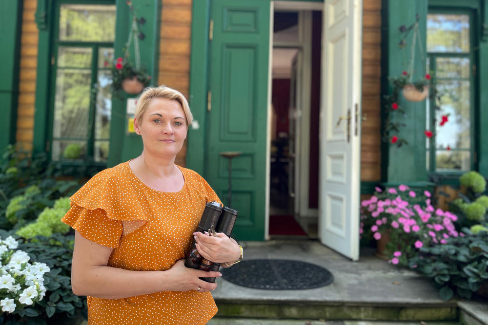 Magdalena Ostrowska stands in front of her restored 19th century hotel and restaurant in Bialowieza, along Poland's border with Belarus. Tensions along this border have meant that Ostrowska's revenue has been cut in half. She says guests cancel their reservations because they are scared of Polish media reports that say Russia's Wagner militia is training just beyond the border in Belarus.