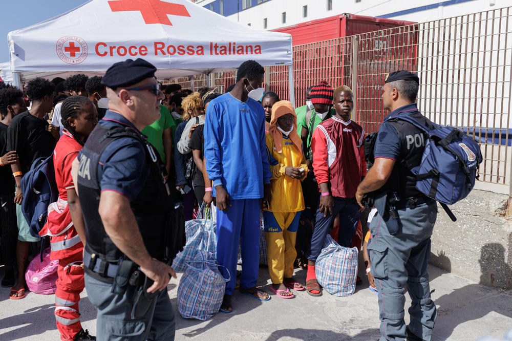 Migrants enter a ferry boarding under the control of police and Italian Red Cross workers, who distribute water and basic items in Lampedusa, Sept. 22.